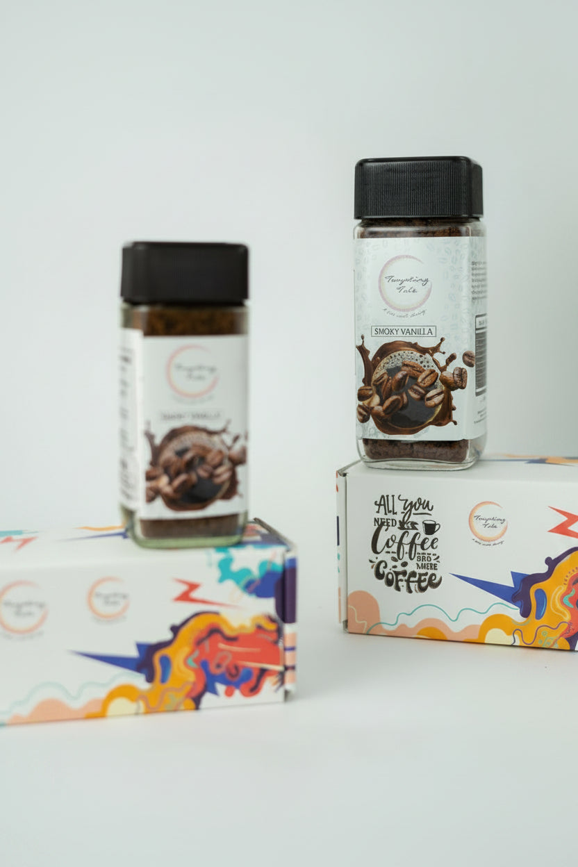Two glass jars of coffee powder with black lids and white labels, displayed on top of and next to colorful branded boxes against a light gray background.